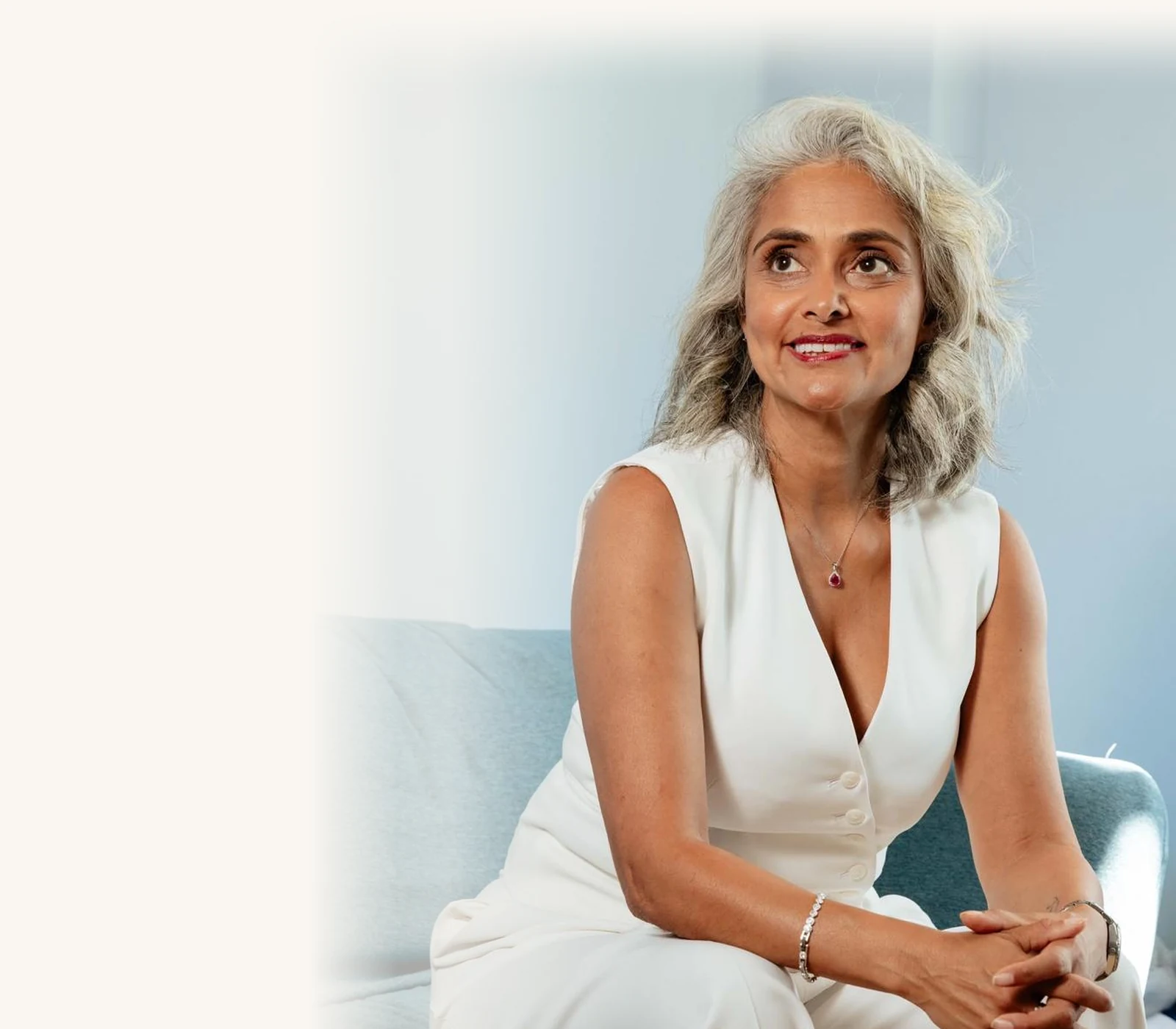 Dimple Amore (Dimple Thakrar) Dimple Amore (Dimple Thakrar), founder of The Dimple Method and host of Beyond the Words, seated portrait in a white tailored suit